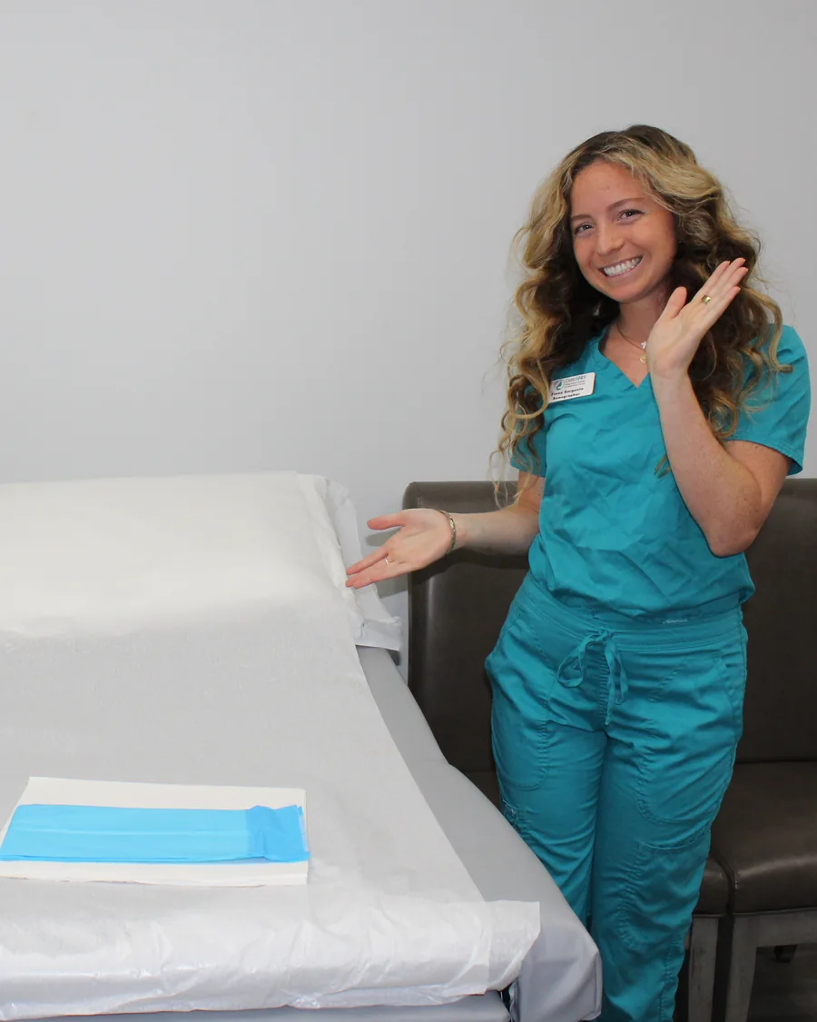 A Care Net sonographer welcoming visitors beside an empty examination table